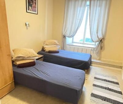 Two beds aligned in a single room, with large window